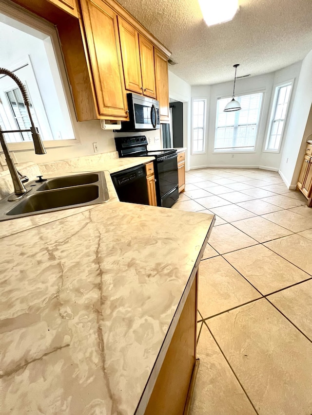 kitchen with pendant lighting, light tile patterned floors, sink, black appliances, and a textured ceiling