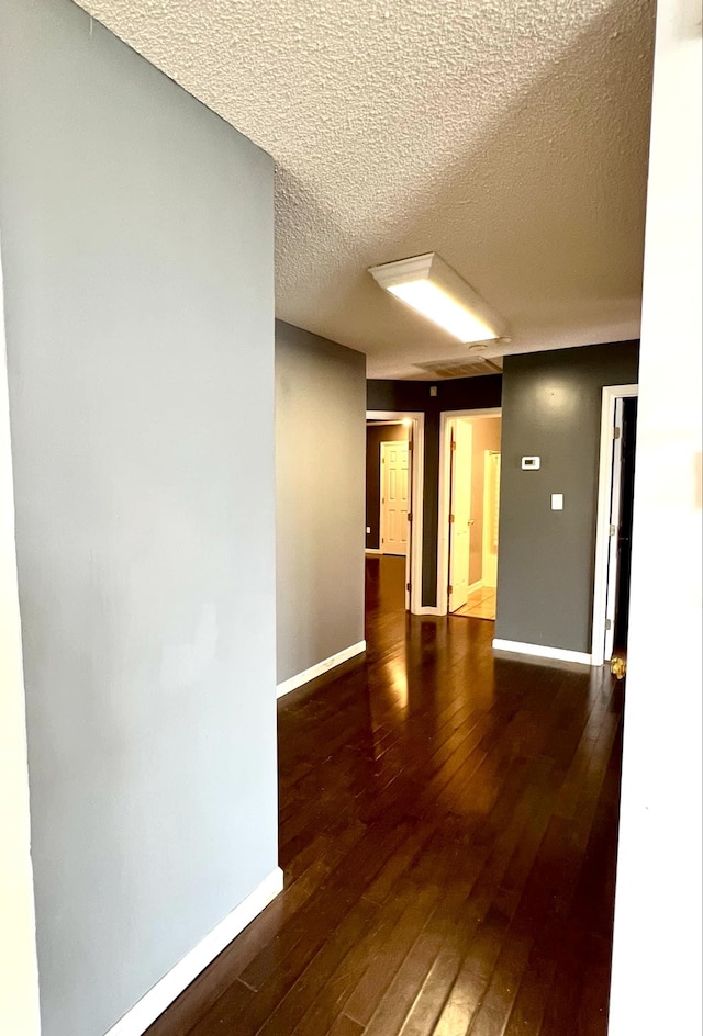 unfurnished room featuring dark wood-type flooring and a textured ceiling