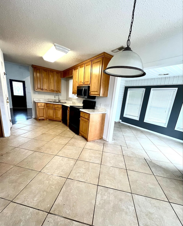 kitchen with decorative light fixtures, sink, light tile patterned floors, black appliances, and a textured ceiling