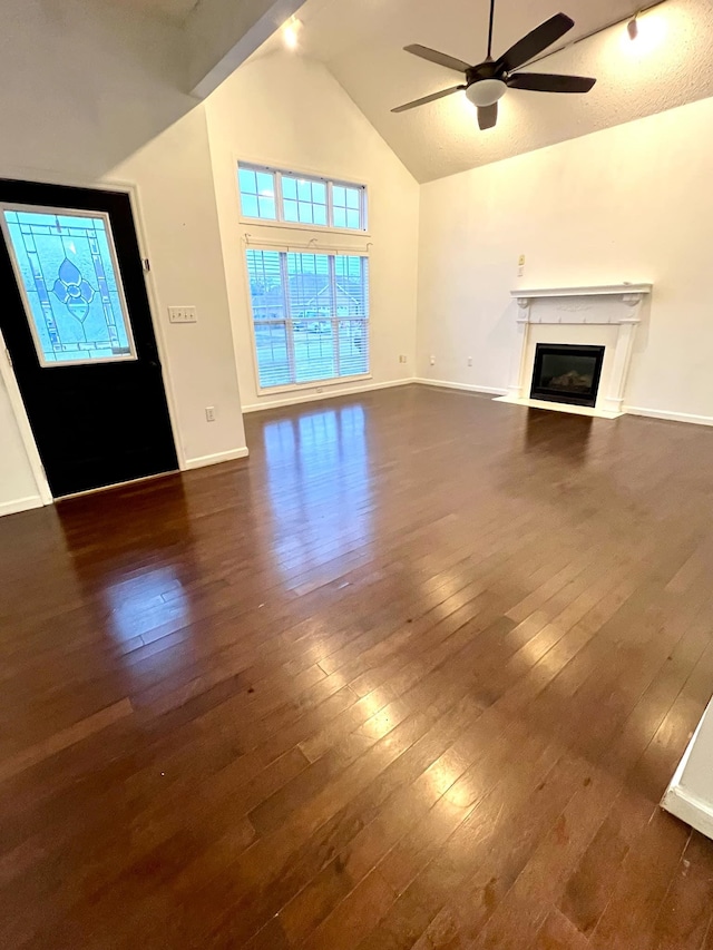 unfurnished living room with ceiling fan, dark hardwood / wood-style flooring, and high vaulted ceiling