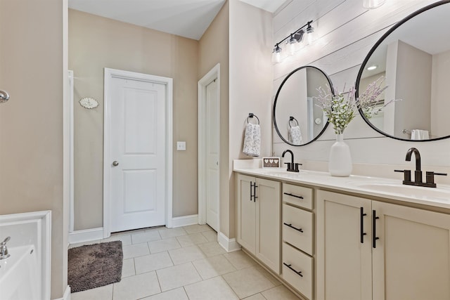 bathroom featuring tile patterned floors, a sink, baseboards, and double vanity