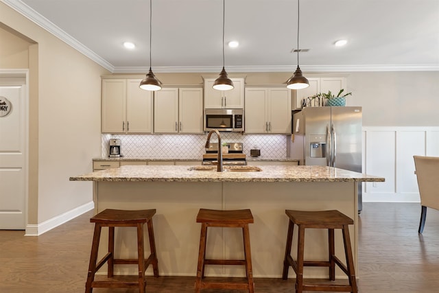 kitchen with a breakfast bar, a center island with sink, stainless steel appliances, and a sink