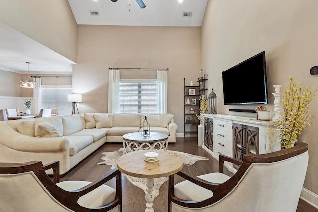 living room with dark wood-type flooring, a high ceiling, and visible vents