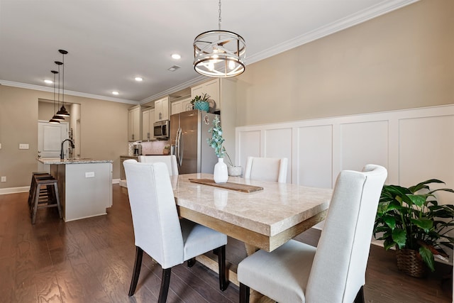 dining room with dark wood-type flooring, ornamental molding, and a decorative wall