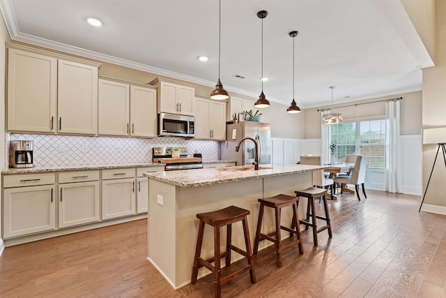 kitchen featuring appliances with stainless steel finishes, light wood-type flooring, a sink, and ornamental molding