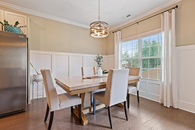 dining room with crown molding, visible vents, a decorative wall, dark wood-type flooring, and a chandelier