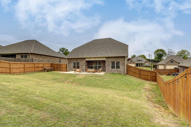 back of property with a fenced backyard, brick siding, a yard, roof with shingles, and a patio area