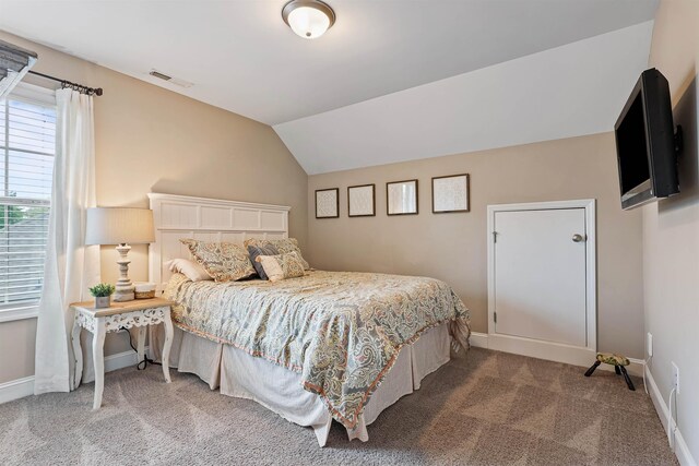 carpeted bedroom featuring lofted ceiling, visible vents, and baseboards