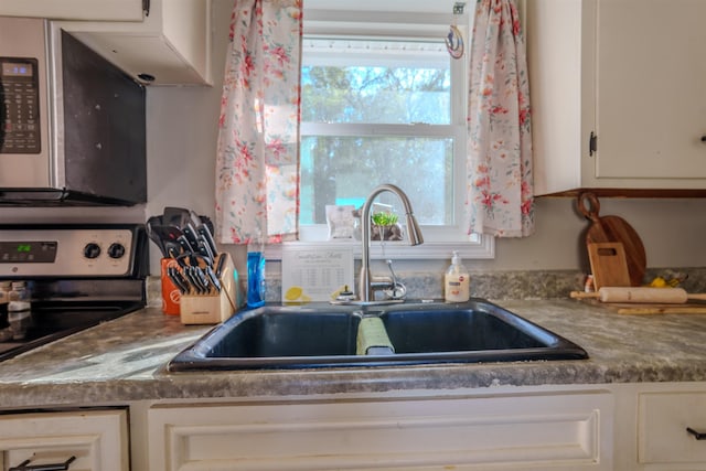 kitchen featuring white cabinets, black electric range, a healthy amount of sunlight, and sink