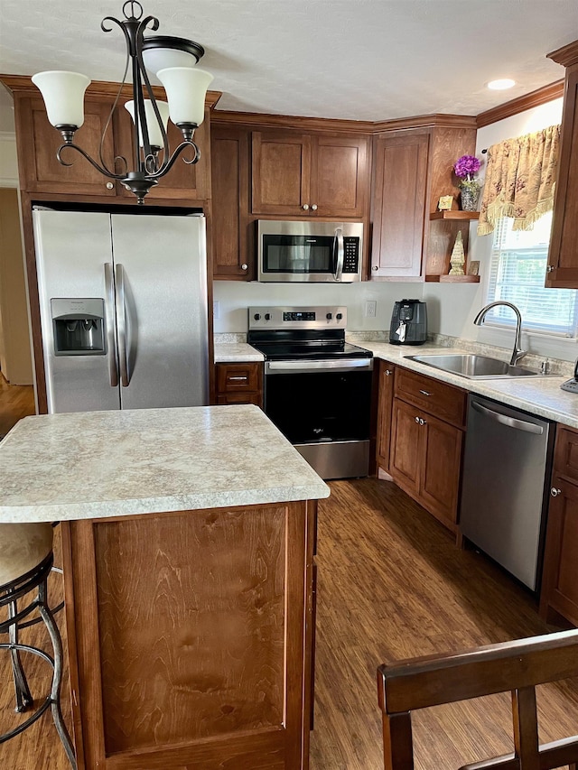 kitchen with sink, dark hardwood / wood-style flooring, decorative light fixtures, a kitchen island, and appliances with stainless steel finishes