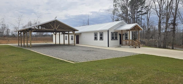 exterior space featuring metal roof, driveway, and a lawn