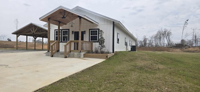 view of front facade featuring a carport, a front lawn, board and batten siding, and central air condition unit