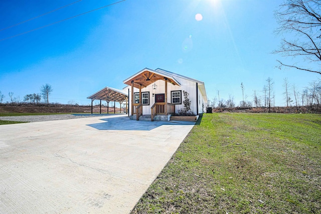 view of front of house featuring board and batten siding, driveway, a carport, and a front lawn