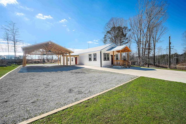 rear view of house featuring a lawn, gravel driveway, and a detached carport