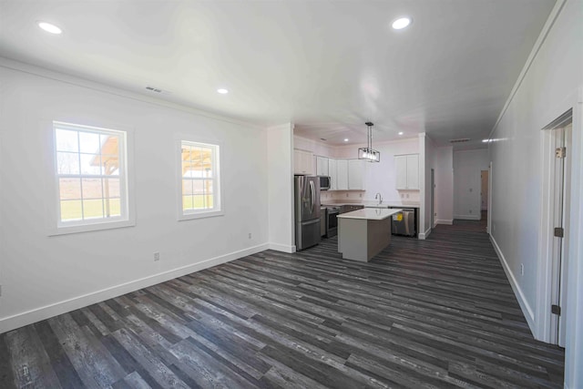 kitchen with a kitchen island, appliances with stainless steel finishes, open floor plan, light countertops, and a sink