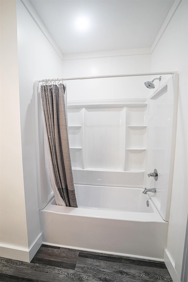 full bath featuring wood finished floors, shower / bath combo with shower curtain, and baseboards