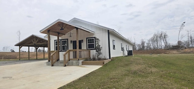 view of front of house featuring board and batten siding, an attached carport, central AC, and a front lawn