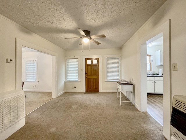 foyer featuring ceiling fan, heating unit, light colored carpet, and a textured ceiling