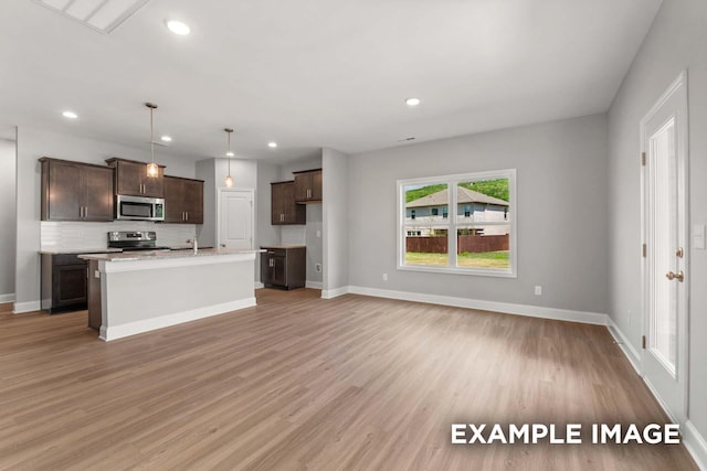 kitchen with light wood-style flooring, decorative backsplash, stainless steel appliances, and a sink