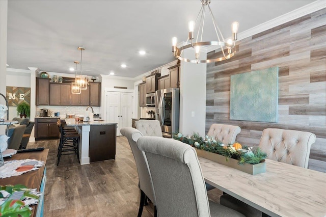 dining room featuring dark wood-type flooring, an inviting chandelier, ornamental molding, and sink