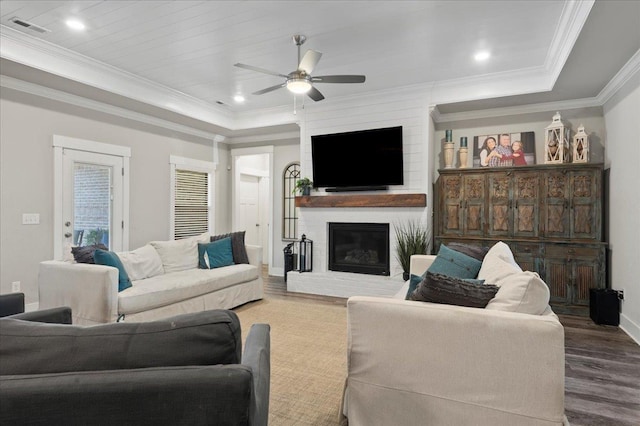 living room with hardwood / wood-style flooring, ceiling fan, ornamental molding, and a brick fireplace