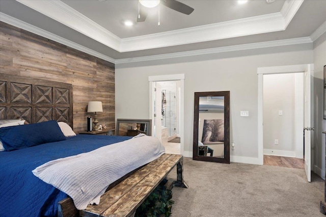 carpeted bedroom featuring a raised ceiling, wooden walls, crown molding, and ceiling fan