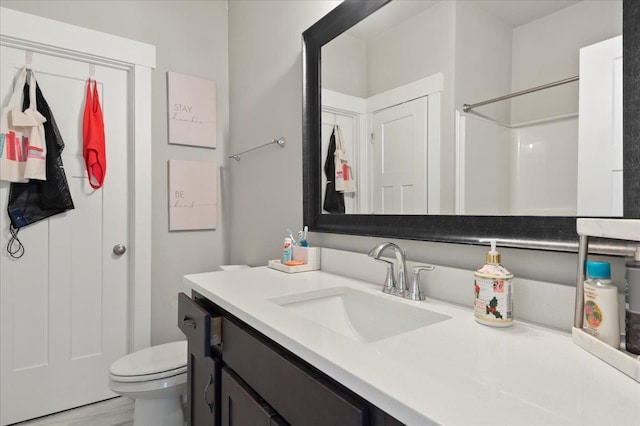 bathroom with wood-type flooring, vanity, toilet, and walk in shower