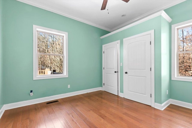 unfurnished bedroom featuring ceiling fan, light hardwood / wood-style flooring, ornamental molding, and multiple windows