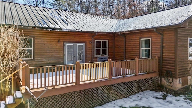 snow covered rear of property with a wooden deck