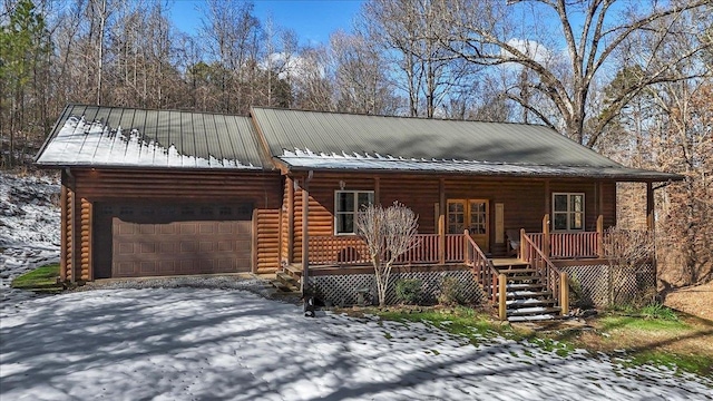 log-style house featuring covered porch and a garage