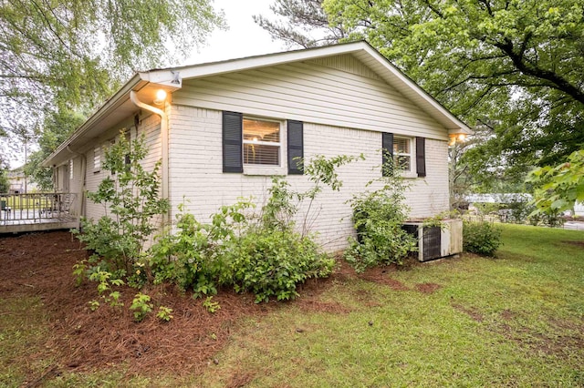  - view of property exterior featuring a lawn, a wooden deck, and brick siding