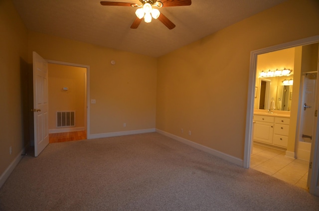 unfurnished bedroom with connected bathroom, light colored carpet, and ceiling fan