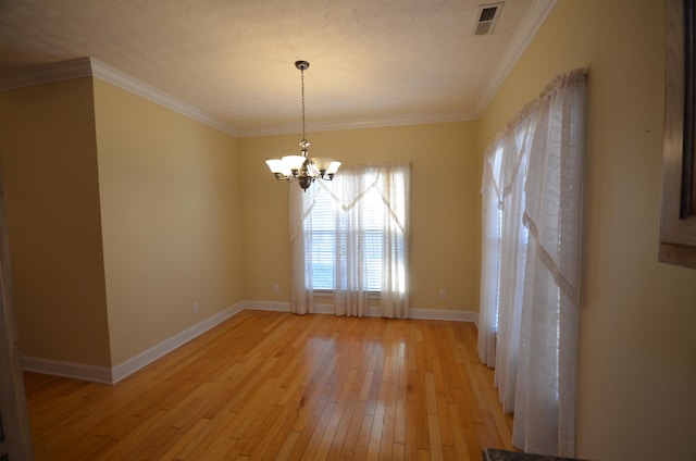 spare room with an inviting chandelier, crown molding, and light wood-type flooring