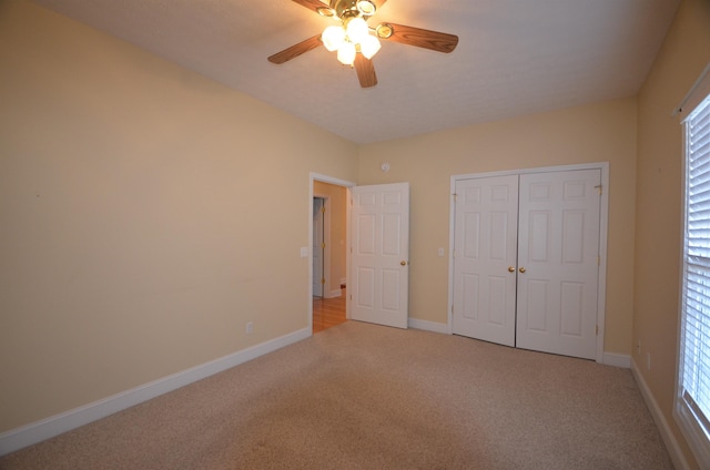 unfurnished bedroom featuring light carpet, ceiling fan, and a closet