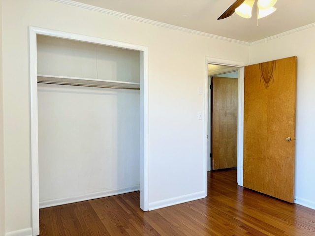 unfurnished bedroom with dark wood-type flooring, ceiling fan, ornamental molding, and a closet