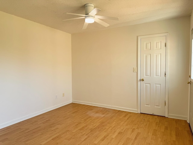 spare room with ceiling fan, light hardwood / wood-style floors, and a textured ceiling