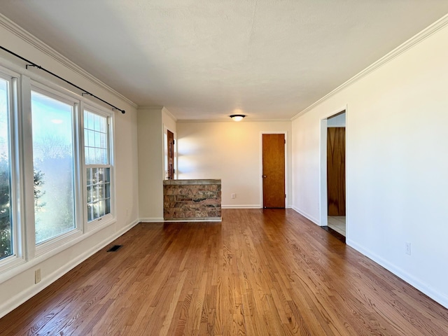 unfurnished room featuring crown molding, a fireplace, and light hardwood / wood-style floors