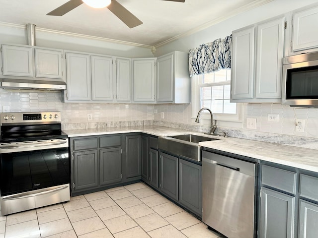 kitchen with sink, crown molding, tasteful backsplash, appliances with stainless steel finishes, and gray cabinets