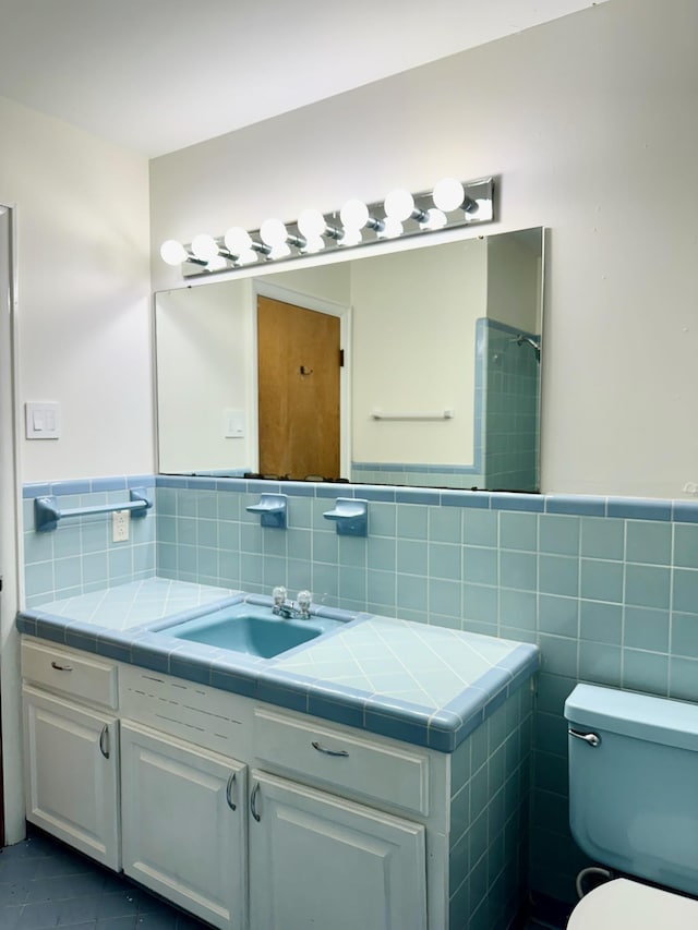 bathroom with tile patterned floors, vanity, toilet, and tile walls