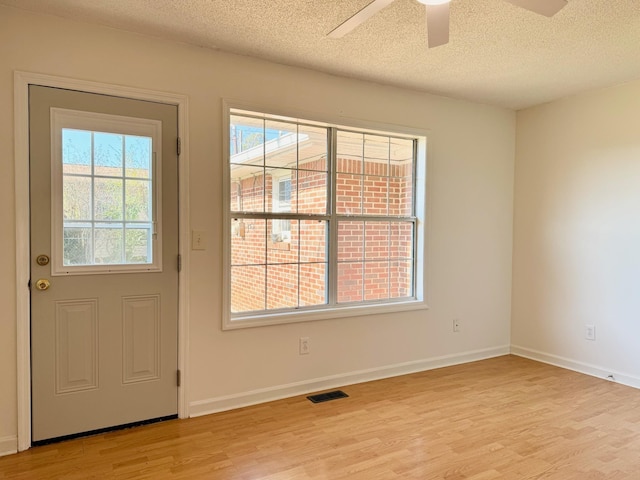 doorway with ceiling fan, a textured ceiling, and light hardwood / wood-style floors