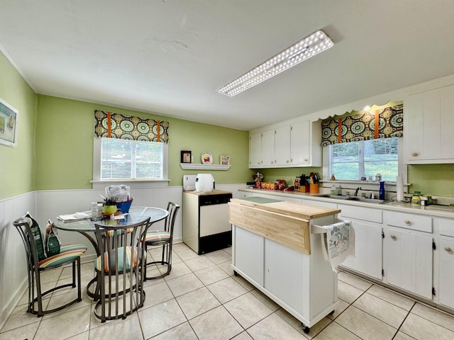  - kitchen featuring healthy amount of natural light, white cabinetry, a kitchen island, a sink, and a wainscoted wall
