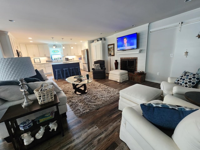 living room featuring dark wood finished floors, a brick fireplace, and recessed lighting