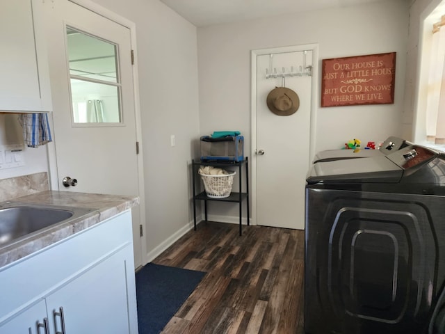 clothes washing area with cabinet space, washing machine and clothes dryer, dark wood finished floors, and baseboards