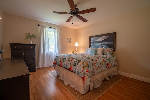 bedroom with baseboards, light wood-style flooring, and a ceiling fan