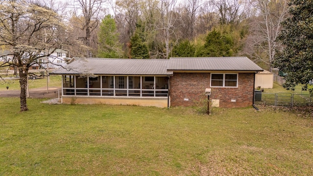 view of front facade featuring metal roof, a sunroom, crawl space, a front yard, and brick siding
