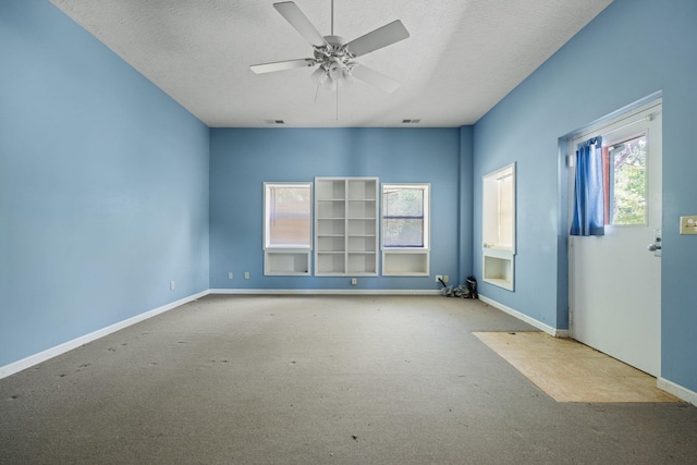 unfurnished room featuring a textured ceiling, carpet floors, and baseboards