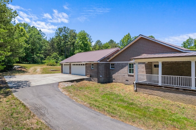 ranch-style home featuring brick siding, an attached garage, crawl space, metal roof, and driveway