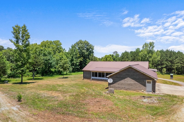 view of front of property featuring driveway, a front lawn, and metal roof