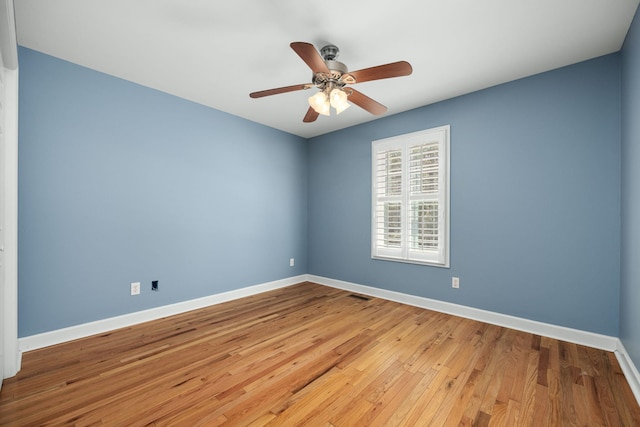 unfurnished room with a ceiling fan, wood-type flooring, visible vents, and baseboards