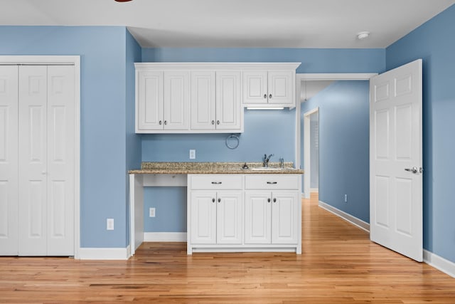 kitchen featuring light wood finished floors, a sink, and white cabinetry